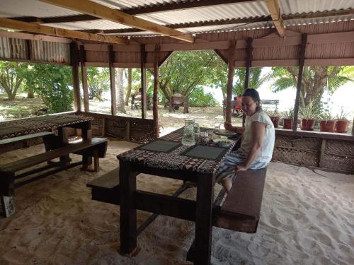 Eine Frau, die an einem Tisch in einem Pavillon sitzt. in der Unterkunft Wai Makare Homestay in Naviti Island