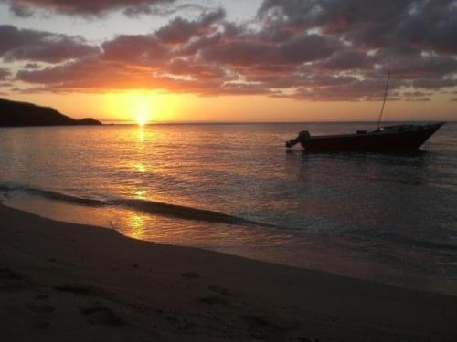 a boat sitting in the ocean at sunset at Wai Makare Homestay in Naviti Island