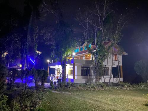 a white house at night with lights at Bloomfield Farmhouse and Eco-Resort in Darjeeling