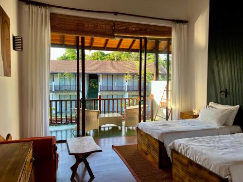 1 dormitorio con 2 camas y vistas a un balcón en Palm Garden Ayurveda Resort, en Ahangama