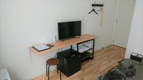 Zimmer mit einem Schreibtisch und einem TV an der Wand in der Unterkunft Sarabetsu-mura chiiki Kouryu Center - Vacation STAY 21683v in Naka-satsunai
