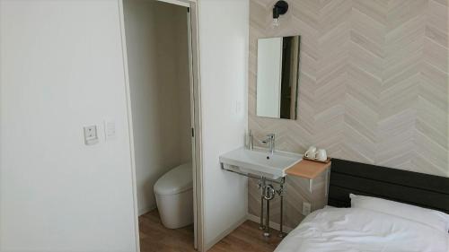 y baño con cama, lavabo y espejo. en Sarabetsu-mura chiiki Kouryu Center - Vacation STAY 21683v, en Naka-satsunai