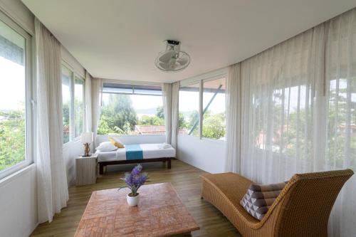 a bedroom with a bed and a couch and a table at Aochalong Villa Resort & Spa - SHA Plus in Chalong