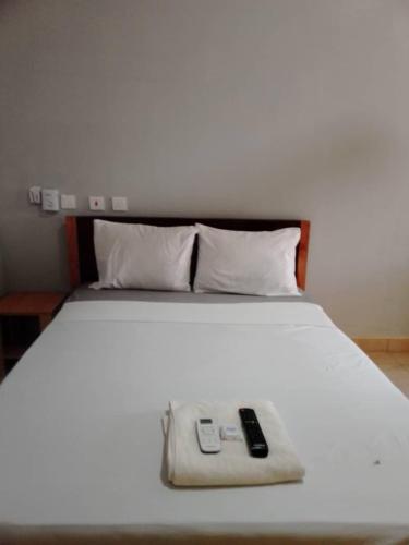 a white bed with two remote controls on it at Danson Lodge Guest House in Pokuase