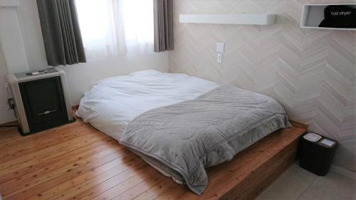 a bedroom with a white bed and a wooden floor at Sarabetsu-mura chiiki Kouryu Center - Vacation STAY 21960v in Naka-satsunai
