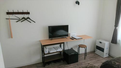 Habitación con escritorio y TV en la pared. en Sarabetsu-mura chiiki Kouryu Center - Vacation STAY 21964v, en Naka-satsunai