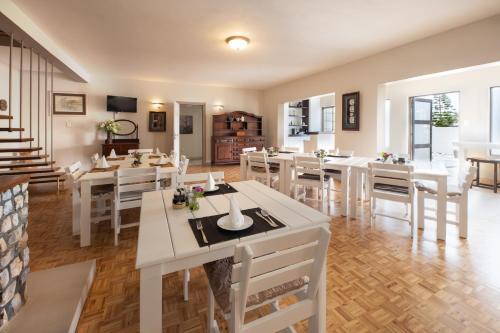 un comedor con mesas blancas y sillas blancas en Guesthouse Fischreiher B&B en Swakopmund