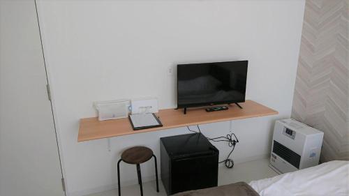 Zimmer mit einem Schreibtisch und einem TV an der Wand in der Unterkunft Sarabetsu-mura chiiki Kouryu Center - Vacation STAY 35300v in Naka-satsunai