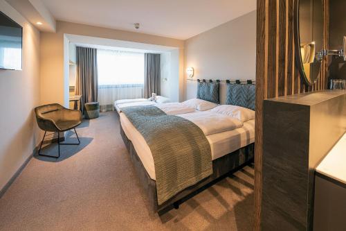 a hotel room with a large bed and a chair at Parkhotel Schmid in Adelsried