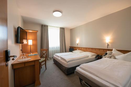 a hotel room with two beds and a television at Parkhotel Schmid in Adelsried