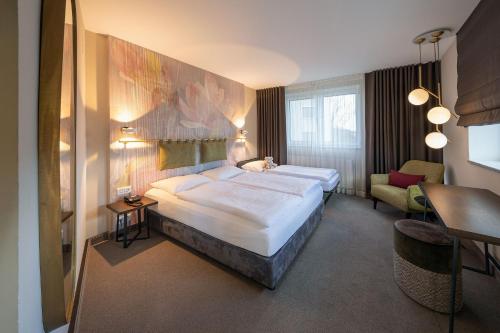 una habitación de hotel con 2 camas y una silla en Parkhotel Schmid, en Adelsried