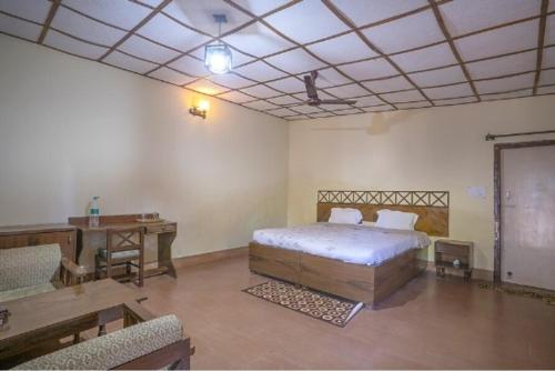 a bedroom with a bed and a desk and a table at Maharaja Kothi Resort, Bandhavgarh in Tāla
