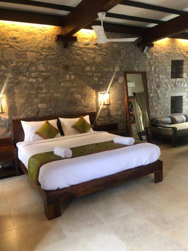 a bedroom with a large bed and a stone wall at Wada1 in Aihole