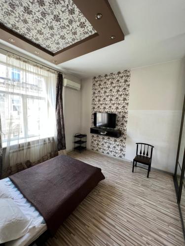 1 dormitorio con 1 cama, TV y ventana en Lviv's University Apartments, en Leópolis