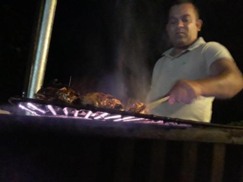 um homem a cozinhar carne em cima de uma grelha em Ella gama village guest house em Diyatalawa