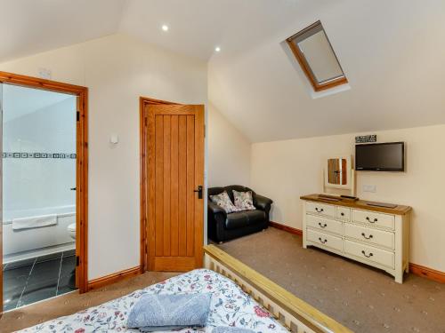 a bedroom with a bed and a chair and a television at Stewner Bank Cottage in Ulverston