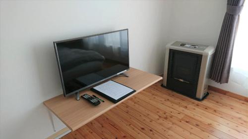 TV de pantalla plana en una mesa de madera en una habitación en Sarabetsu-mura chiiki Kouryu Center - Vacation STAY 25698v, en Sarabetsu