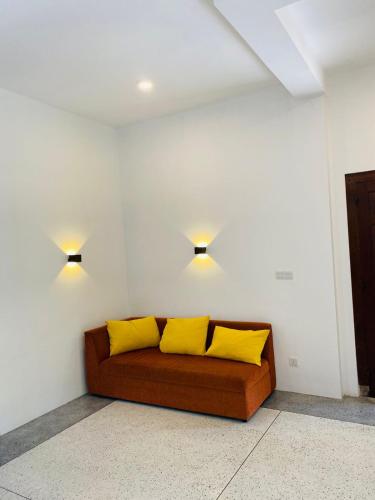 a couch with two yellow pillows in a room at Oshi villa in Unawatuna