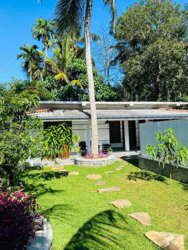 烏納瓦圖納的住宿－Oshi villa，一座花园,在一座建筑前种有棕榈树