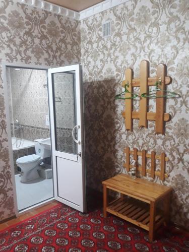 a bathroom with a toilet and a bench in it at Guest House Orzu in Khiva
