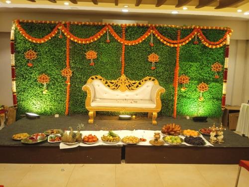 a table with a couch in front of a stage with food at Kohinoor Hotels in Erode