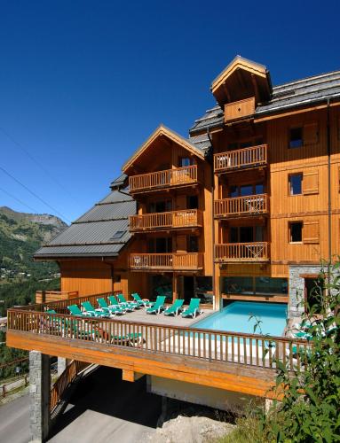 un bâtiment avec une piscine et des chaises sur un pont dans l'établissement Résidence Odalys Le Hameau et les Chalets de la Vallée d'Or, à Valloire
