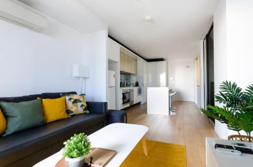 a living room with a couch and a table at 2BR CBD pad, city views, free parking, pool, gym in Melbourne