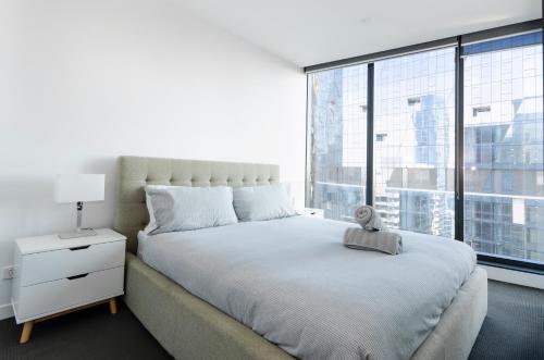 une chambre avec un lit et une grande fenêtre dans l'établissement 2BR CBD pad, city views, free parking, pool, gym, à Melbourne