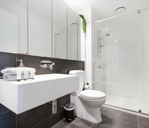 La salle de bains est pourvue d'un lavabo, de toilettes et d'une douche. dans l'établissement 2BR CBD pad, city views, free parking, pool, gym, à Melbourne