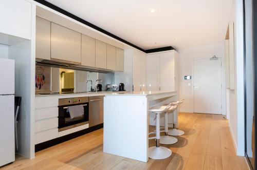 a kitchen with white cabinets and a counter with stools at 2BR CBD pad, city views, free parking, pool, gym in Melbourne