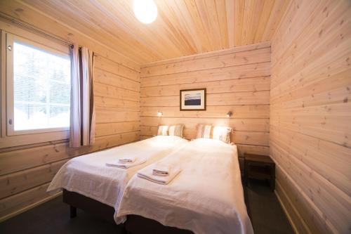 een slaapkamer met een bed in een houten kamer bij Ounasvaaran Lakituvat Chalets in Rovaniemi