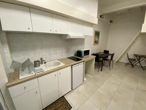 uma cozinha com armários brancos, um lavatório e uma mesa em La Caverne - Studio au Capitole em Toulouse