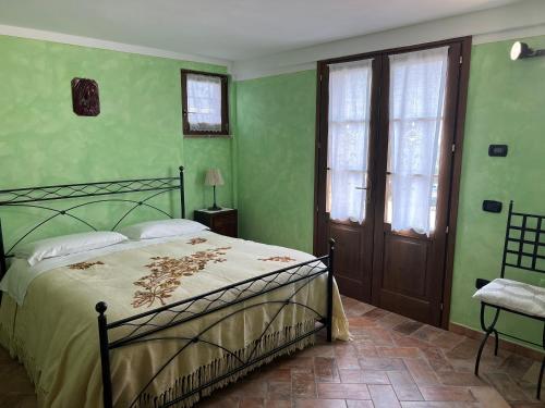 een slaapkamer met groene muren, een bed en een raam bij Villetta Toscana - Montepulciano in Montepulciano