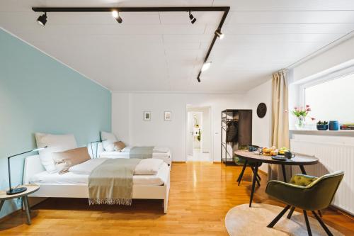 Dormitorio blanco con cama y mesa en Sali Homes - Mozart EINS, en Bietigheim-Bissingen