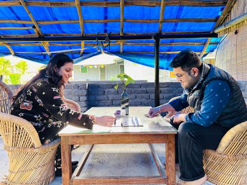 a man and a woman sitting at a table at Dreamwoods A travellers farm in Dharamshala