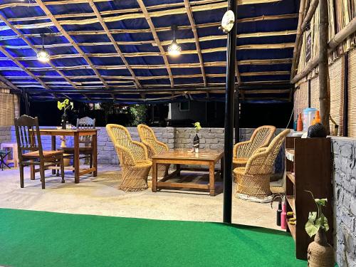 a patio with a table and chairs on a green floor at Dreamwoods A travellers farm in Dharamshala
