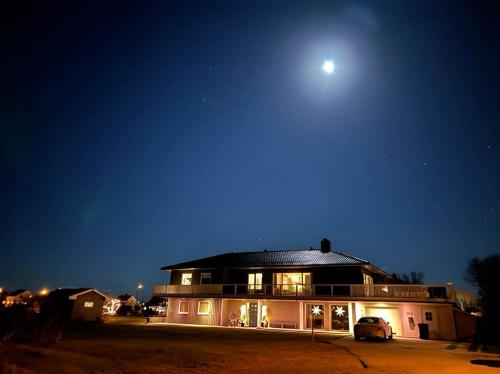 Una casa de noche con la luna en el cielo en Apartment Utsikten, en Andenes