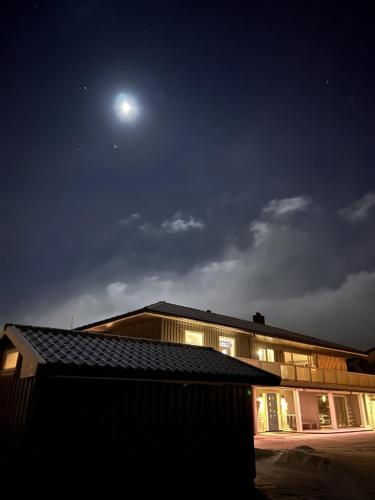a building at night with the moon in the sky at Apartment Utsikten in Andenes