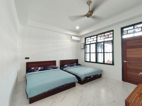 2 camas en una habitación con 2 ventanas en Nanyang Homestay 3 rooms 10 pax- Ground Floor en Sibu