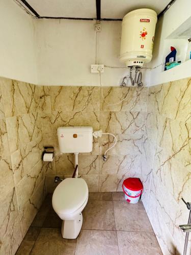 a bathroom with a toilet in a stone wall at Dreamwoods A travellers farm in Dharamshala