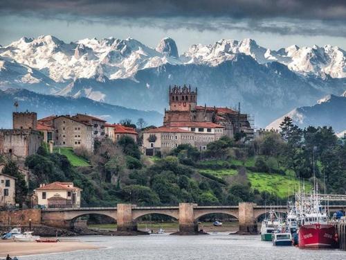 a town on a hill with a bridge and snowy mountains at Las Tres Mimosas in San Vicente de la Barquera