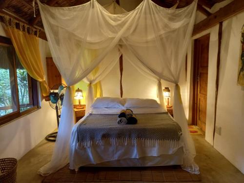 a bedroom with a bed with a canopy at Casa Camaleao Gekko Cottadge in Praia do Tofo