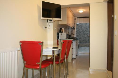 cocina con sillas rojas y mesa con TV en Marmara Apartments, en Estambul