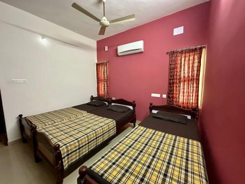 a bedroom with two beds and a ceiling fan at Chidambaram Spiritual Stay in Chidambaram