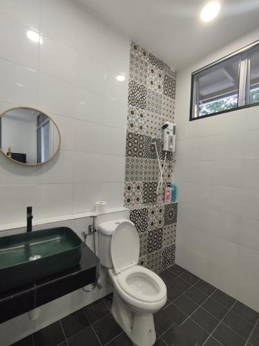 a bathroom with a toilet and a sink and a mirror at Nanyang Homestay 3 rooms 10 pax- Ground Floor in Sibu