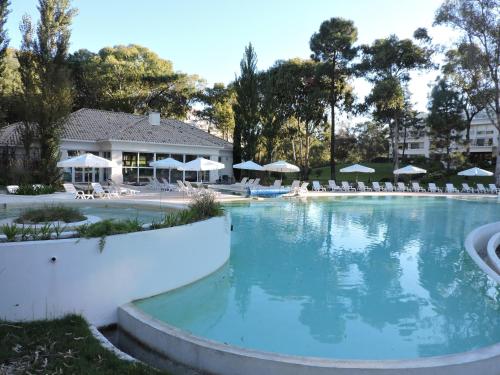 una grande piscina con sedie bianche e ombrelloni di Green Park - Lloret de Mar Punta del Este a Punta del Este
