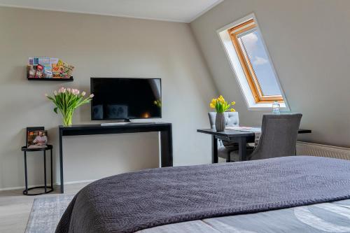 een slaapkamer met een bed, een tv en een bureau bij Liv Inn in Hillegom