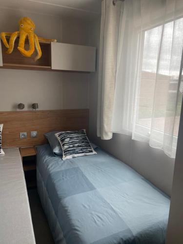 1 cama en un dormitorio con un osito de peluche amarillo en la ventana en A Casa Mia Plage, en Hermanville-sur-Mer