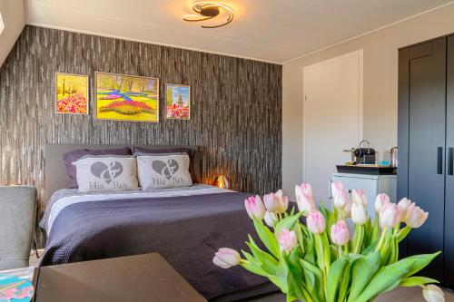 a bedroom with a bed and a table with pink tulips at Liv Inn Hillegom in Hillegom