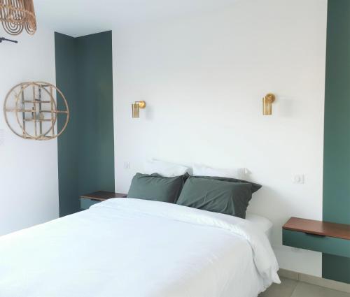 - une chambre avec un lit blanc et des murs bleus dans l'établissement Au Jardin des Deux Roches, à Prissé